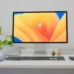 Minimalist office desk setup with computer, keyboard, and greenery.