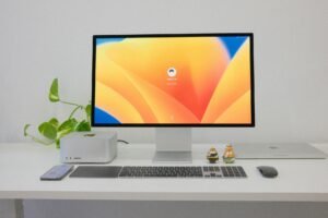 Minimalist office desk setup with computer, keyboard, and greenery.